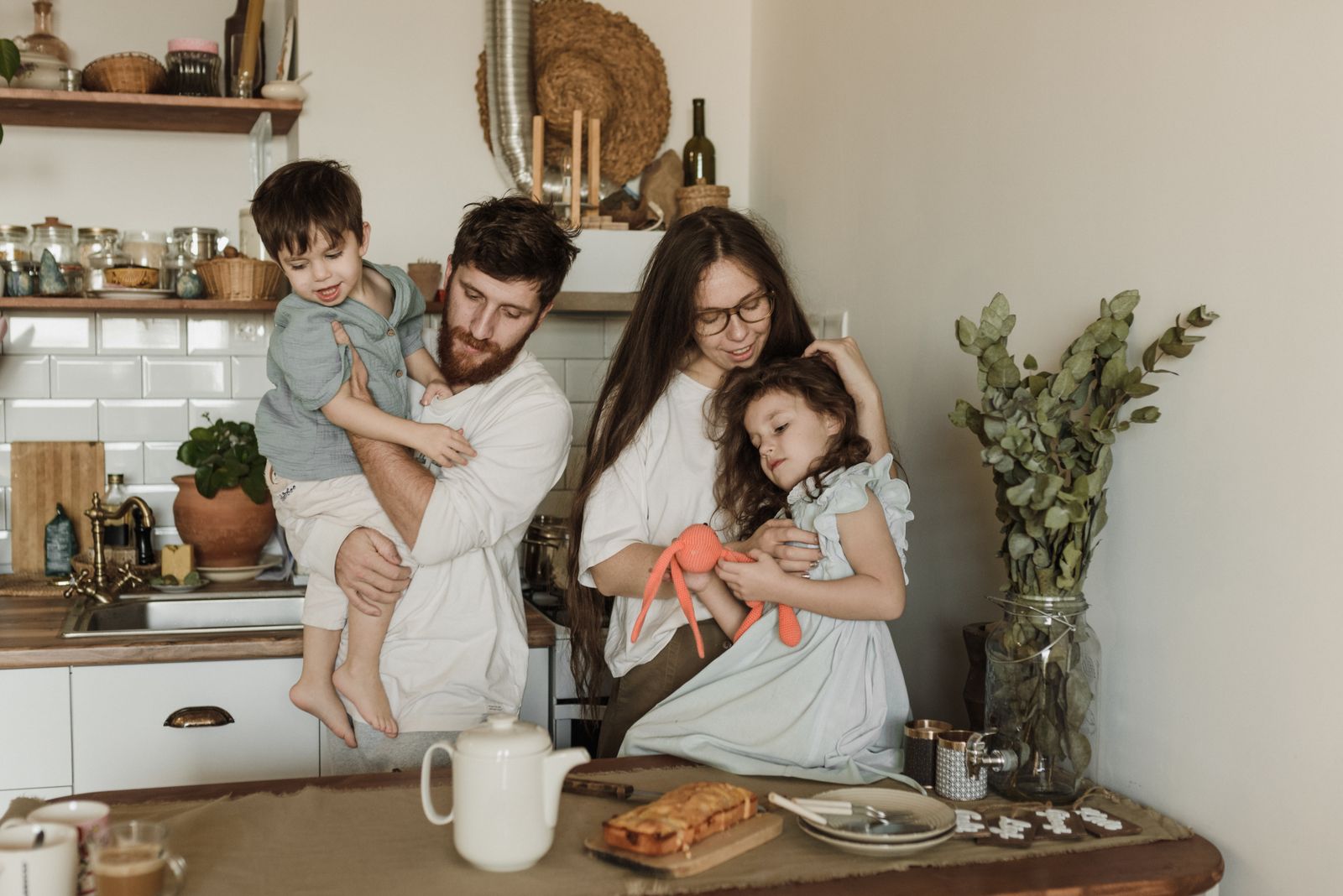 Two parents and their two young children together at the kitchen bench